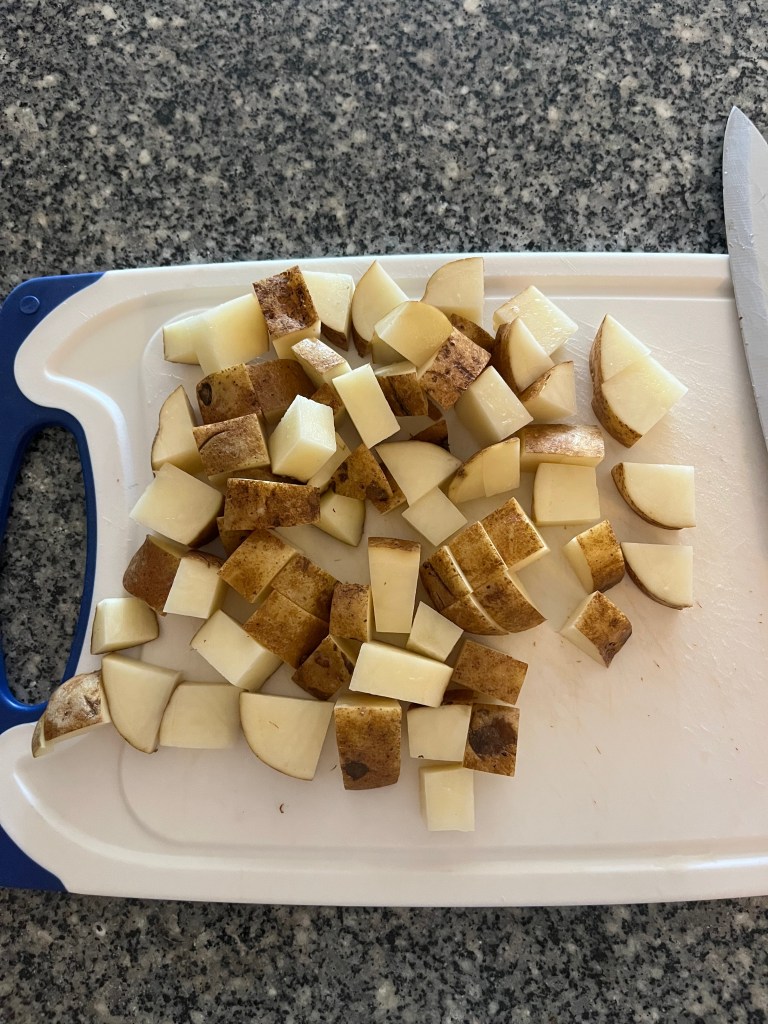 A white cutting board with chopped potatoes. 
