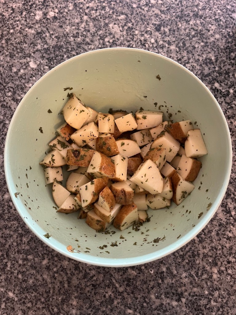 A blue bowl with seasoned chopped potatoes. 