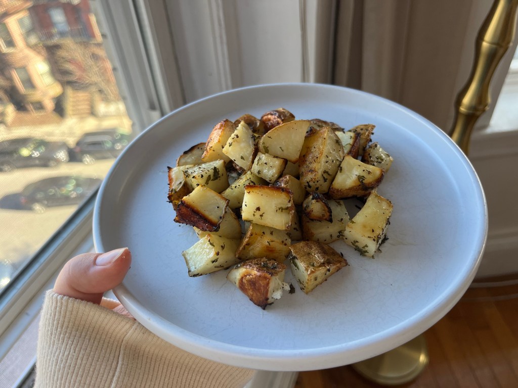 A white plate with roasted potatoes.