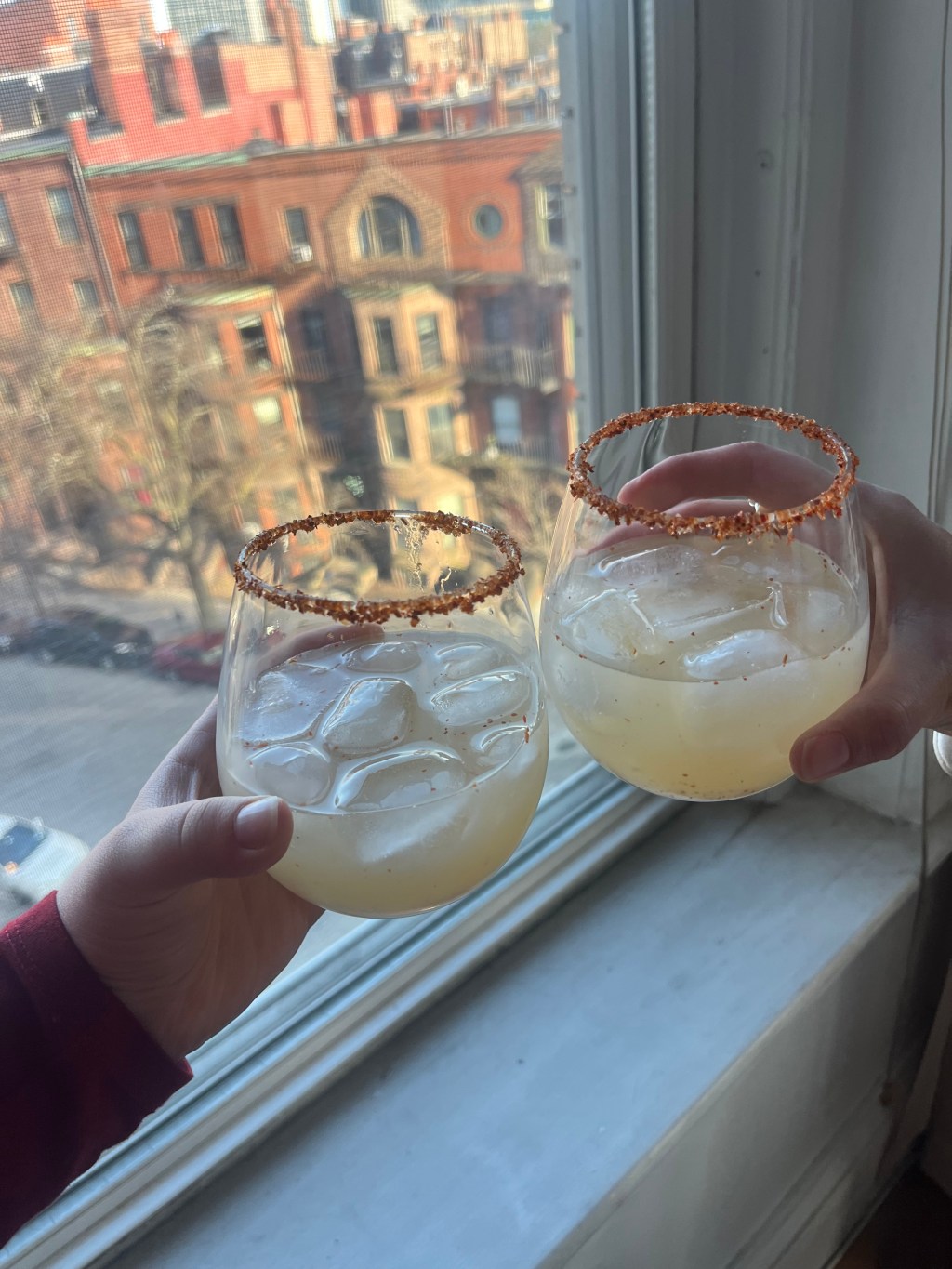 Two margaritas in stemless wine glasses rimmed with Tajin.